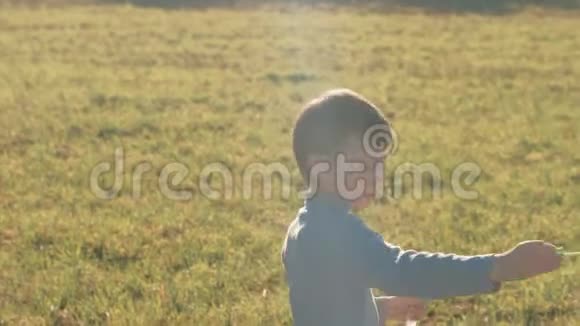 男孩在草地上做肥皂泡在温暖的春天玩耍视频的预览图