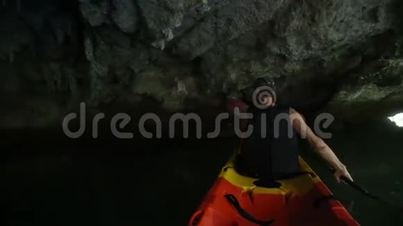 长者强壮男子在黑暗洞沿河划船视频的预览图
