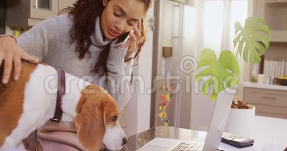 穿着冬装的快乐女人一边抚摸宠物一边接电话4K4k视频的预览图