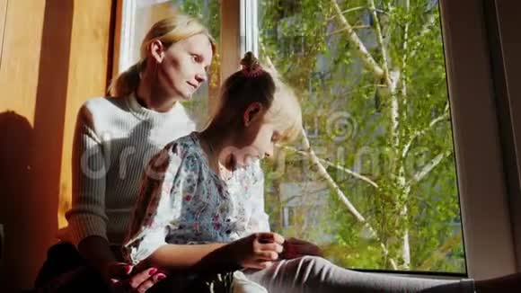 妈妈和女儿6岁坐在窗台上望着窗外窗外是春天是绿色视频的预览图