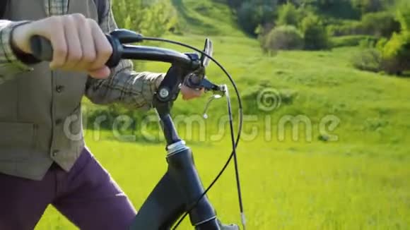 一个人驾驶自行车穿过一片绿色的草地你可以看到他的手和自行车的舵视频的预览图