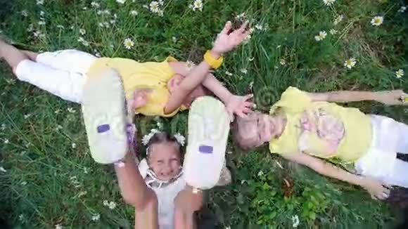 从上面看孩子们躺在草地上洋甘菊草地上向上伸展双手他们玩得很开心夏季视频的预览图