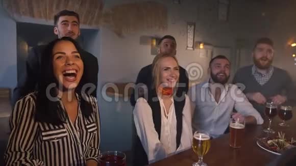 朋友们为他们最喜欢的球队欢呼和在黑暗的酒吧喝啤酒的特写镜头视频的预览图