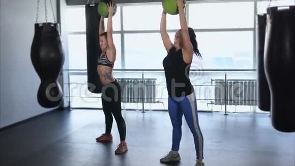 两个女人正在健身把球举到头上视频的预览图