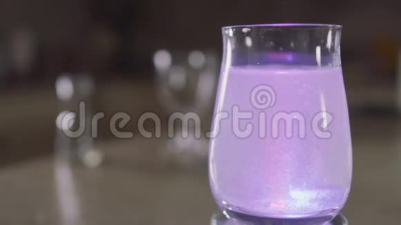 泡腾片溶解在玻璃与水和闪闪发光的彩色灯视频的预览图