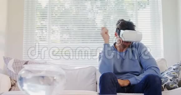 坐在沙发上体验虚拟现实耳机的年轻人视频的预览图