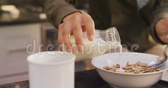 厨房里的女人用玉米片倒牛奶视频的预览图