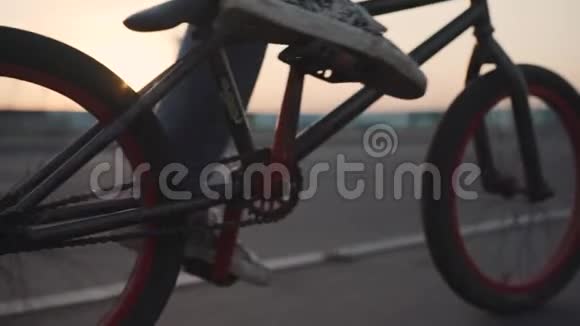 骑自行车的人在日落时骑在他的BMX户外慢动作特写视频的预览图