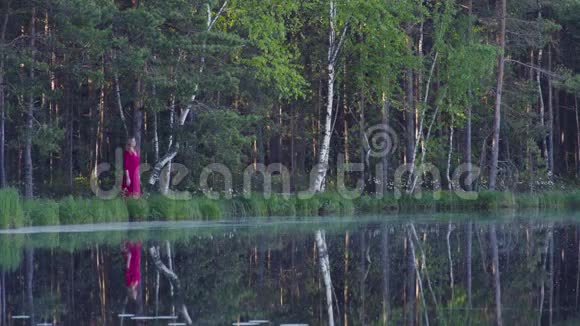 站在湖边森林里的年轻女子视频的预览图
