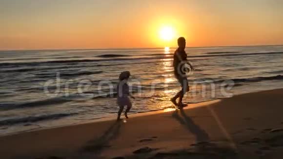 父亲和女儿在日落时沿着海滩奔跑视频的预览图