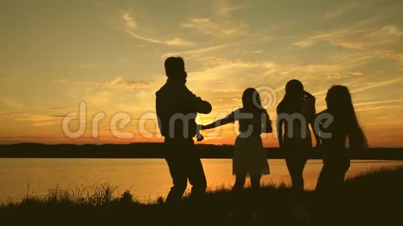 快乐的家庭在海滩上跳舞湖边聚会孩子们跳舞快乐的女孩在海滩上跳舞慢动作美丽美丽视频的预览图
