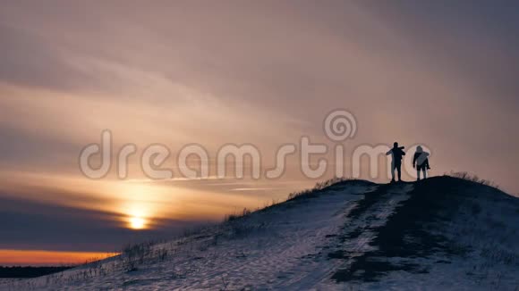 人们冬天跳跃剪影喜雪阳光一群游客走在夕阳的剪影之上视频的预览图