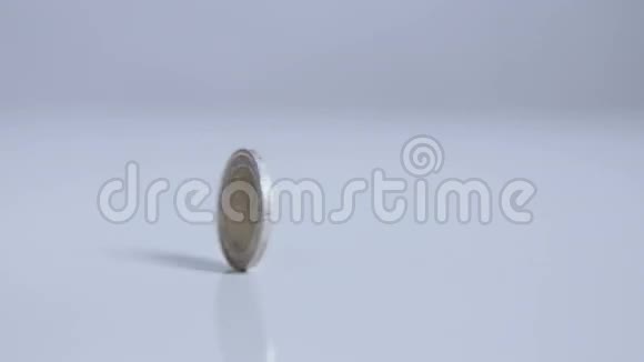 两欧元硬币在一个地方滚动在白色表面缓慢运动视频的预览图