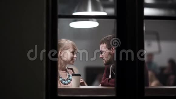 通过窗口查看年轻漂亮夫妇的浪漫约会漂亮的男人和女人坐在咖啡馆里视频的预览图