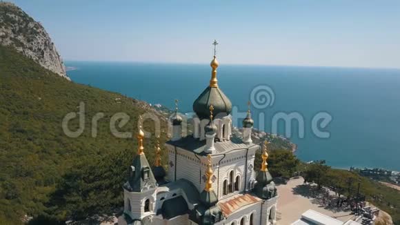 峭壁上的东正教教堂背景是大海和山脉佛洛斯教堂俯瞰图视频的预览图