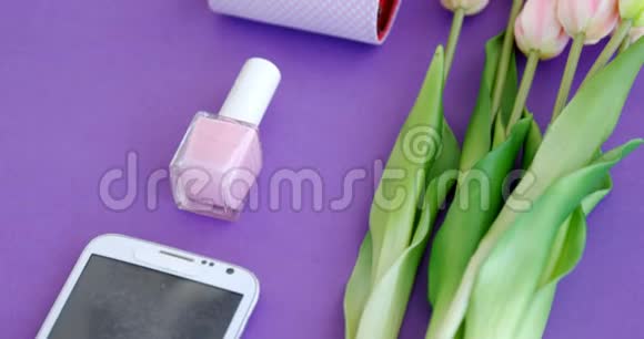 紫色背景4k的鲜花钱包指甲漆和手机视频的预览图