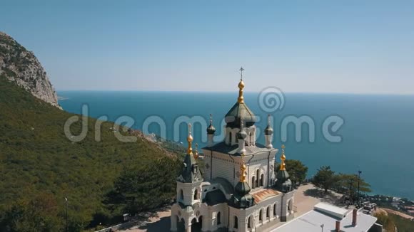 峭壁上的东正教教堂背景是大海和山脉佛洛斯教堂俯瞰图视频的预览图