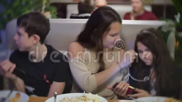 一群朋友坐在咖啡馆里聊天听着智能手机上的音乐推着一段慢动作视频争论不休视频的预览图