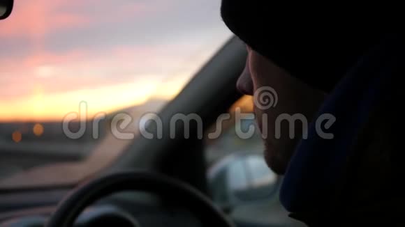 帽子里的司机坐在汽车的车轮后面迎接日落高清1920x1080慢动作视频的预览图