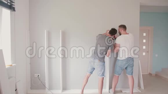 两个年轻人在明亮的公寓里修理男人把家具组装在一起视频的预览图