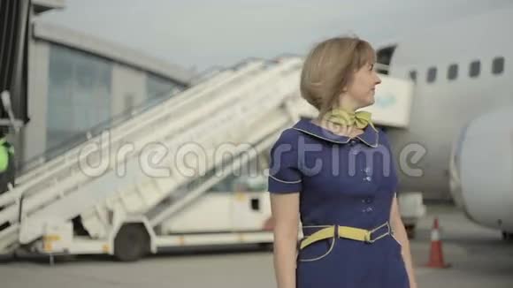 金发空姐站在飞机梯子的背景上视频的预览图
