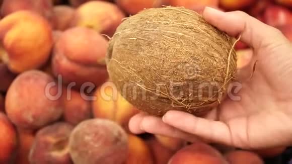 在新鲜桃子的背景下雌性手中的椰子视频的预览图