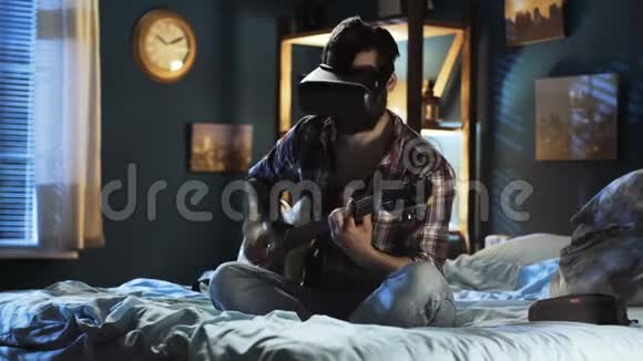 在床上戴着VR眼镜弹吉他的男人视频的预览图
