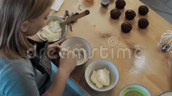 年轻美丽的女人混合奶油装饰纸杯蛋糕的俯视图厨房里的女人做饭视频的预览图