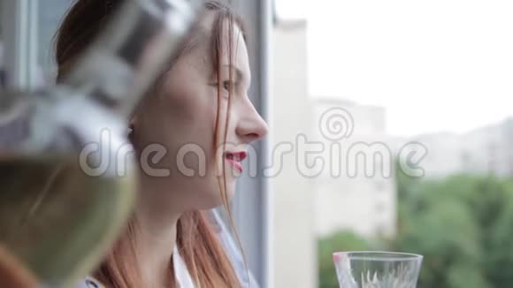 姑娘倒了一杯白酒一个年轻女孩在窗边喝白葡萄酒视频的预览图