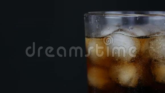 在一个透明的长玻璃杯中的冰泡在黑色背景上近距离观看视频的预览图