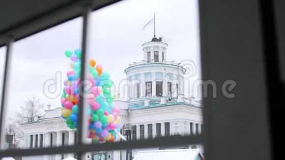 在建筑背景下窗外的一束五颜六色的气球视频的预览图