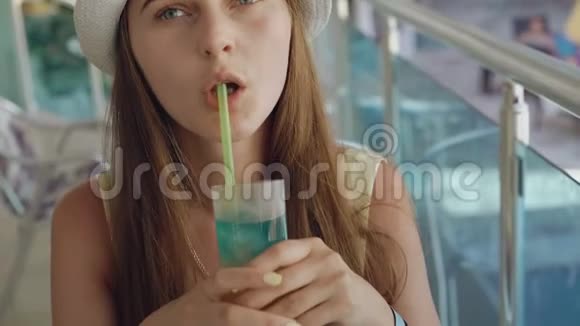 微笑的女孩喝着柠檬水在阳光明媚的阳台上看着海滩视频的预览图