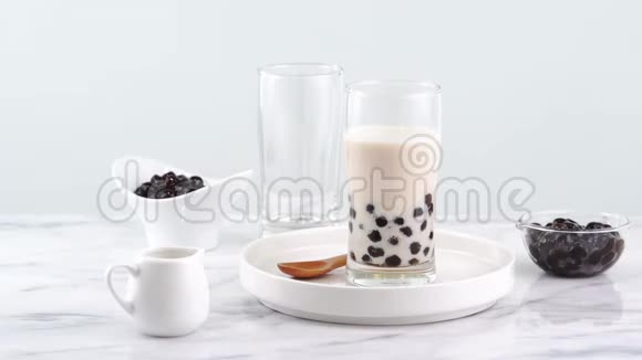 美味的木薯珍珠泡奶茶在玻璃流行饮料在台湾明亮的大理石桌子和白色托盘自制的概念4K视频的预览图