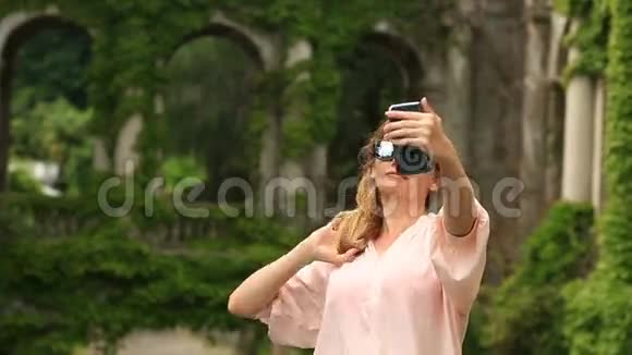 一个旅游的女孩为一座扭曲着常春藤的古老城堡的美丽拼贴画拍照视频的预览图