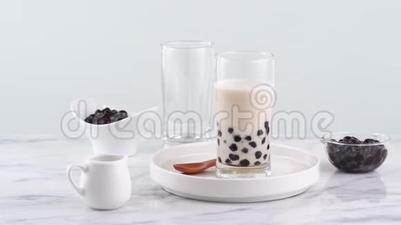 美味的木薯珍珠泡奶茶在玻璃流行饮料在台湾明亮的大理石桌子和白色托盘自制的概念4K视频的预览图