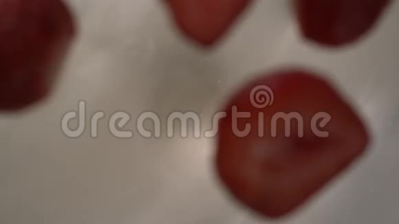 草莓切成两片落在白色奶油状的漩涡中在高速桌面上视频的预览图