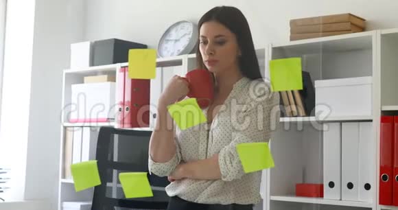 女商人穿着白色衬衫考虑在办公室的玻璃上贴上贴纸视频的预览图