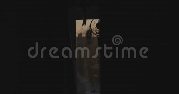 照相机向右向左移动在一个黑暗的房间里太阳光线从里面射出来把捕梦者移开视频的预览图