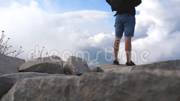 不可辨认的男性徒步旅行者背包站在山顶享受美丽的景观多云的天空视频的预览图