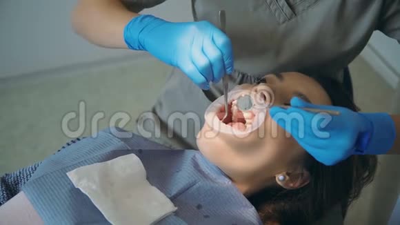 年轻女子去牙科诊所女性躺在牙科椅上医生抛光和清洁她的牙齿视频的预览图