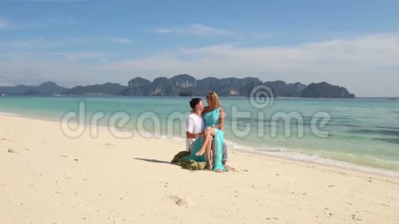 男人在石头上与金发女郎接吻在海边谈视频的预览图
