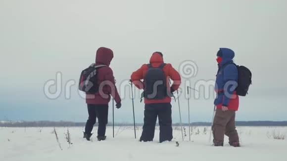 三个徒步旅行者带着徒步旅行杆背包和雪鞋的后景带背包的快乐徒步旅行者小组视频的预览图