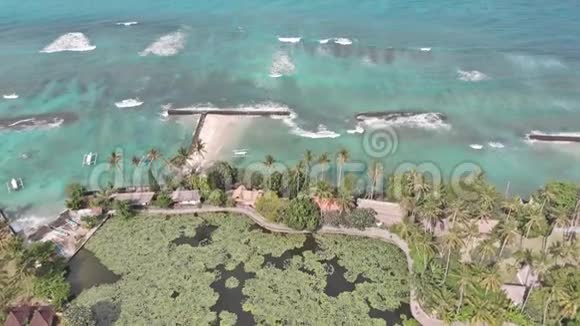 空中镜头飞越热带岛屿巴厘岛海岸线当地村庄和度假胜地走向海浪海洋视频的预览图