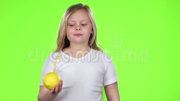 小女孩拿着一个柠檬用吸管从柠檬里喝果汁绿色屏幕慢动作视频的预览图