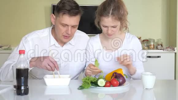 妻子和丈夫坐在桌子旁吃中国面条和新鲜蔬菜适当营养的概念视频的预览图