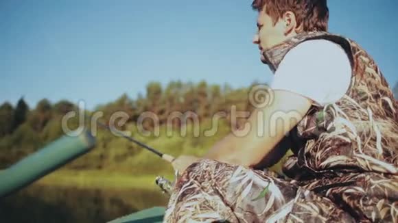 独自一人坐在橡皮船上在湖边钓鱼雄握钓竿捻转纺视频的预览图