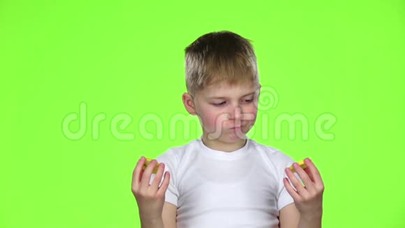 小男孩拿着一片柠檬舔和卷曲的酸绿色屏幕慢动作视频的预览图