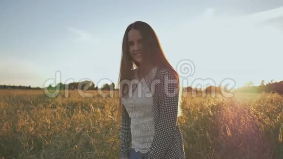 夕阳西下一个年轻的女孩从幸福中跳出来在麦田的背景下视频的预览图