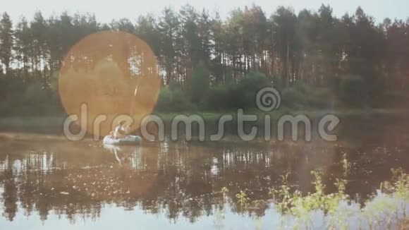 两个人早上在充气船上一起钓鱼森林湖泊和阳光的美丽景观视频的预览图