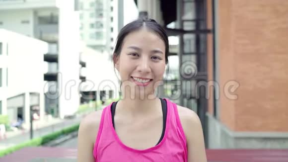 健康美丽的年轻亚洲跑步女子在城市的街头跑步后感到快乐的微笑和寻找相机视频的预览图